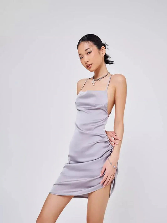 Model showcasing the Silken Rush satin-effect mini dress in a luminous silver-gray hue with ruching.
