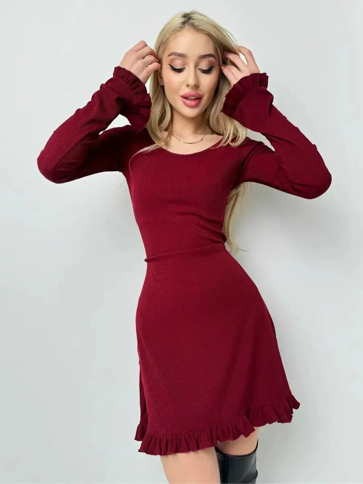 Model wearing the Crimson Flare ribbed knit red dress with ruffle details and a fitted silhouette.