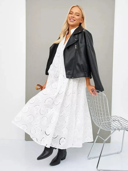 Stylish woman in a Broderie Cotton Maxi Dress with flared sleeves, paired with a leather jacket and ankle boots.