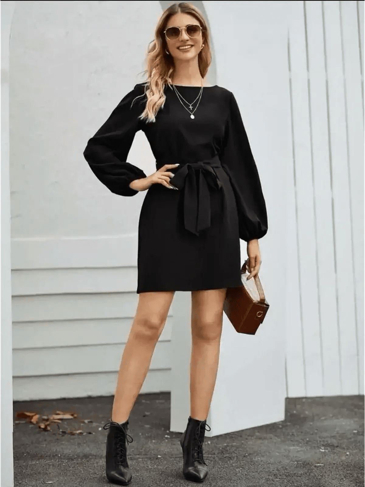 Stylish woman in a black mini dress with long sleeves and tie belt, perfect for formal and cocktail occasions.
