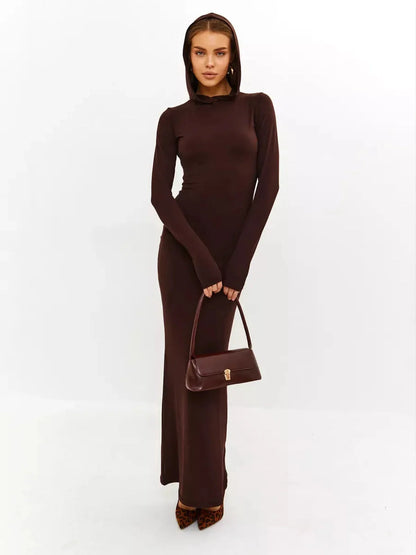 Model wearing Sculpt Maxi Dress in rich chocolate, showcasing hooded design and sleek silhouette with stylish handbag.