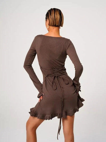 Back view of a woman in a Mocha Flare ribbed knit mini dress with flared cuffs and ruffled hem, showcasing elegant style.
