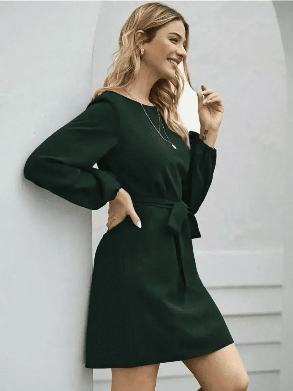 Elegant dark emerald green mini dress with long sleeves and tie detail, perfect for casual or formal occasions.