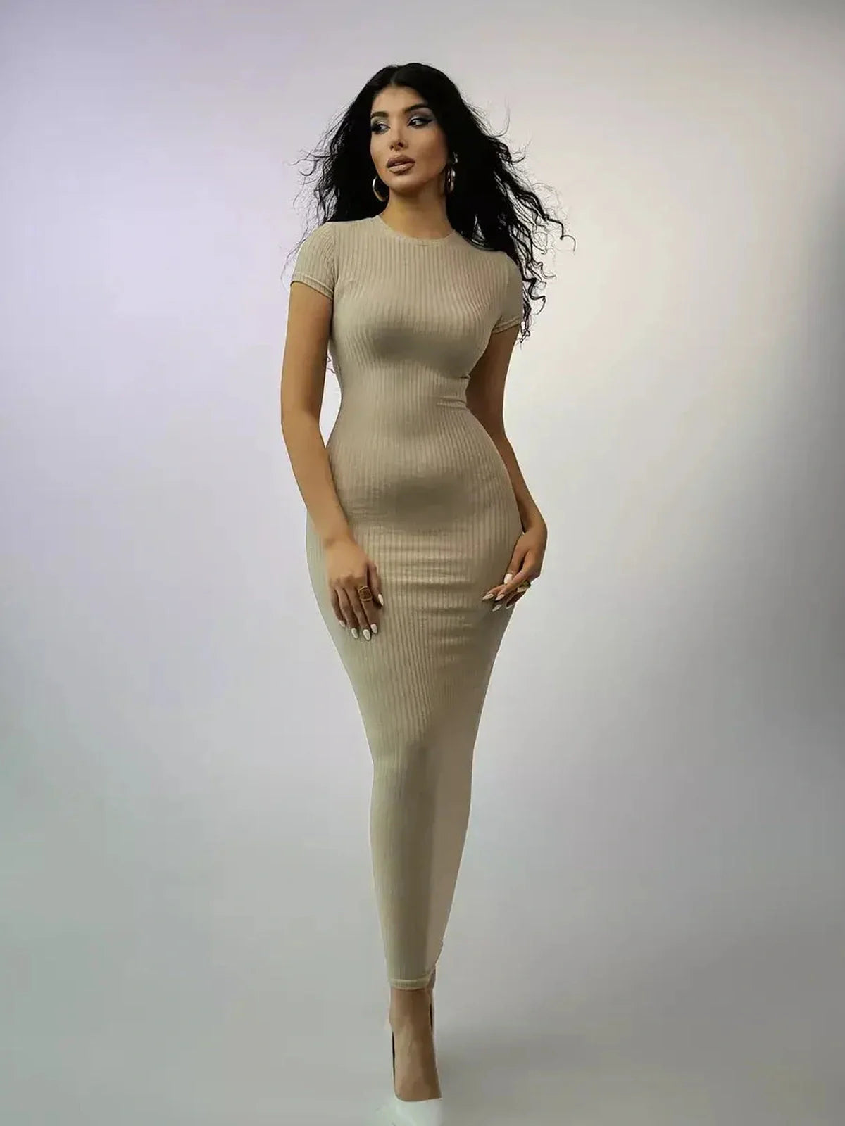 Model showcasing the Contour Grace Maxi Dress, a ribbed knit piece with a sculpted fit in a soft beige color.