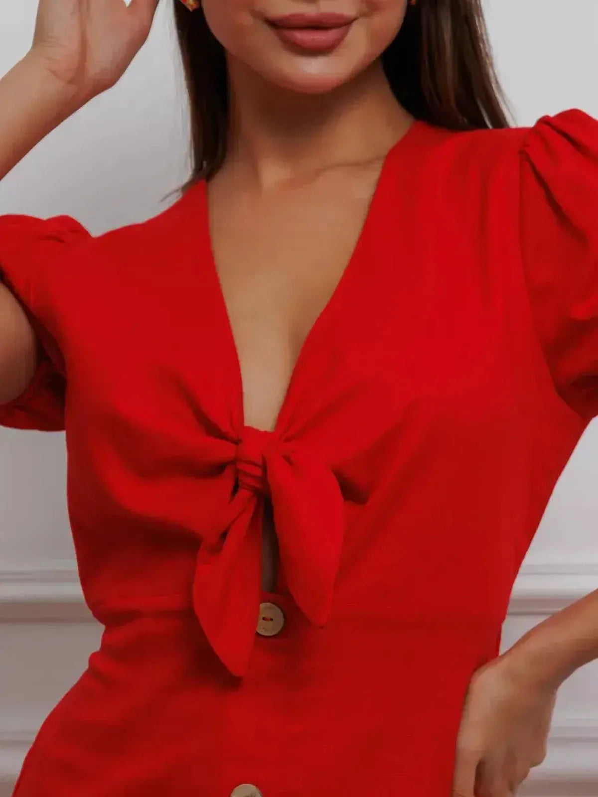 Close-up of a woman wearing a red Maxi Dress Riviera Flame with a tie-front bodice and puff sleeves.