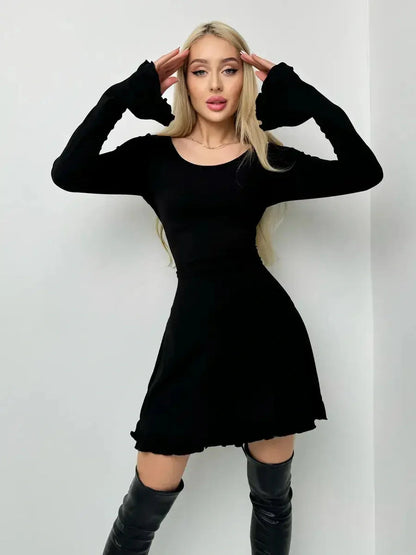 Model wearing the Velvet Lace Mini black dress, showcasing long sleeves and playful ruffled hem.