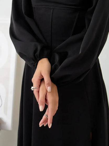 Elegant detail of the Velvet Aura corset dress showcasing the fitted bodice and flowing bishop sleeves in black.