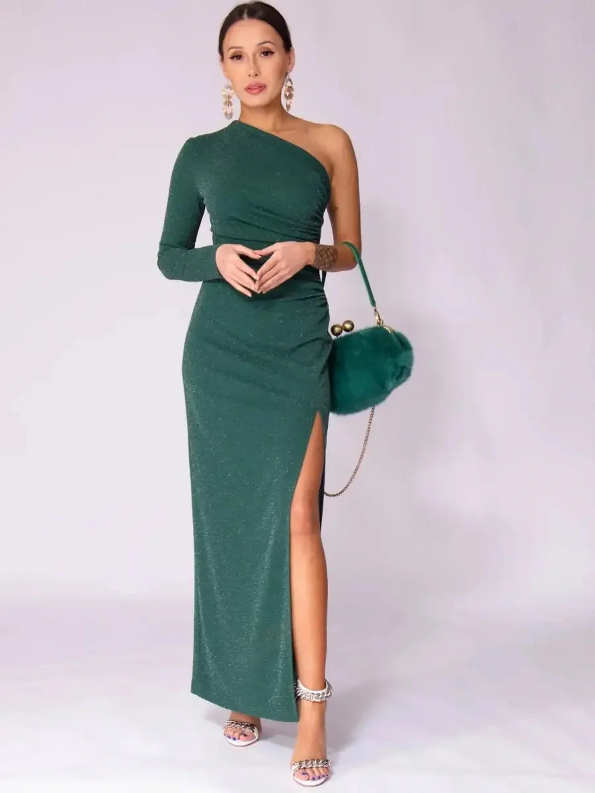 Model wearing Emerald Spark Maxi Dress featuring one-shoulder design, shimmery green fabric, and high side slit.