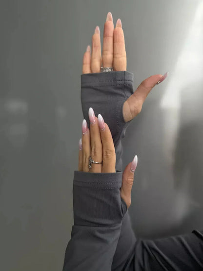 Close-up of hands wearing gray long sleeve dress with unique fingerless design, showcasing stylish nails.