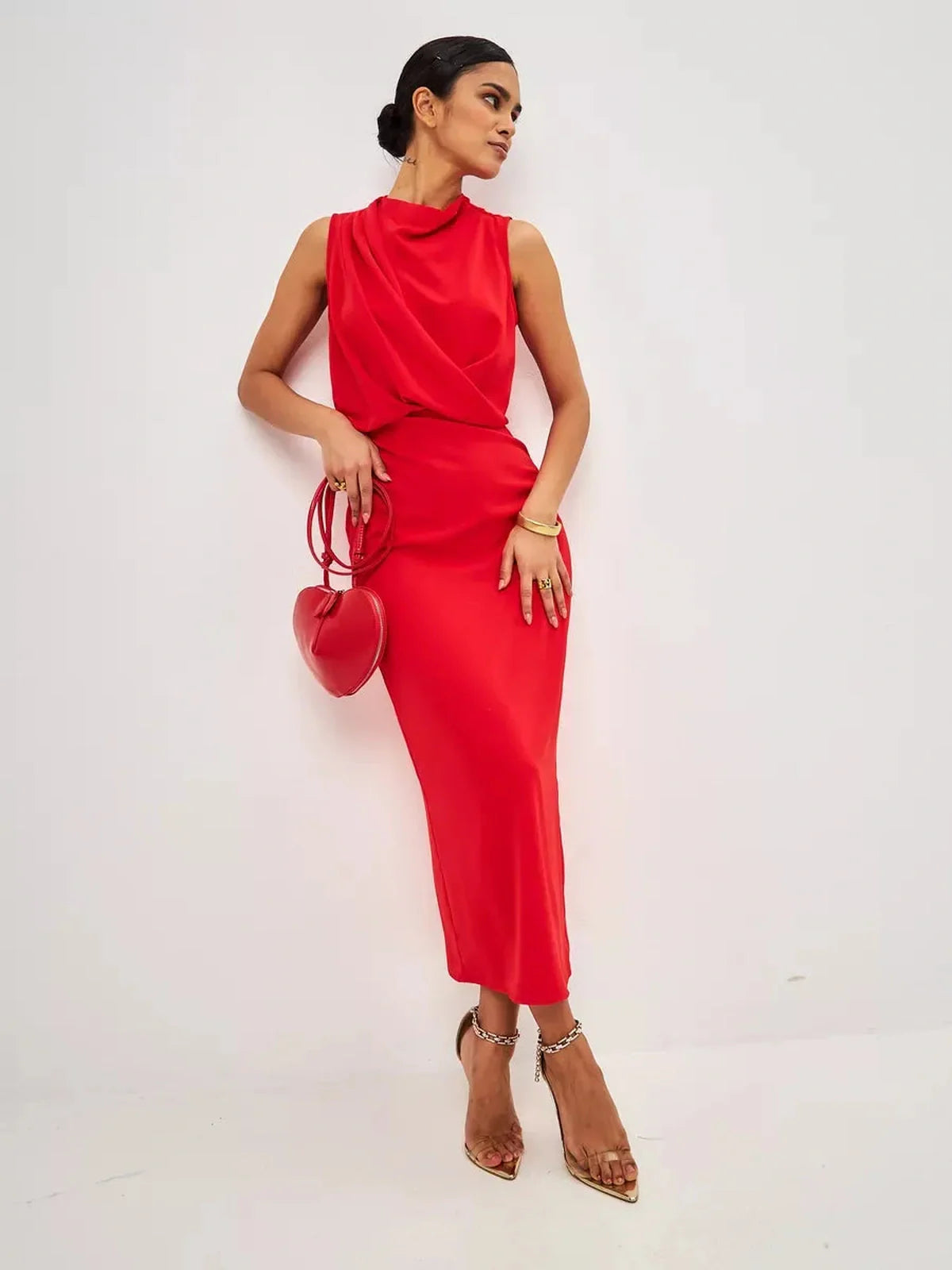 Stylish woman in a red drape maxi dress holding a heart-shaped bag, showcasing elegance and sophistication.