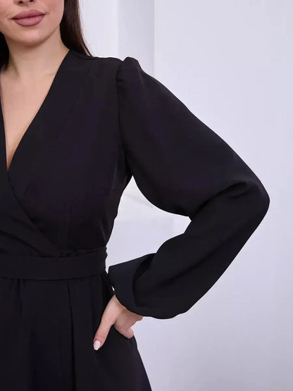 Detail of a black mini dress with a V-neckline and long sleeves, showcasing timeless elegance and sophistication.