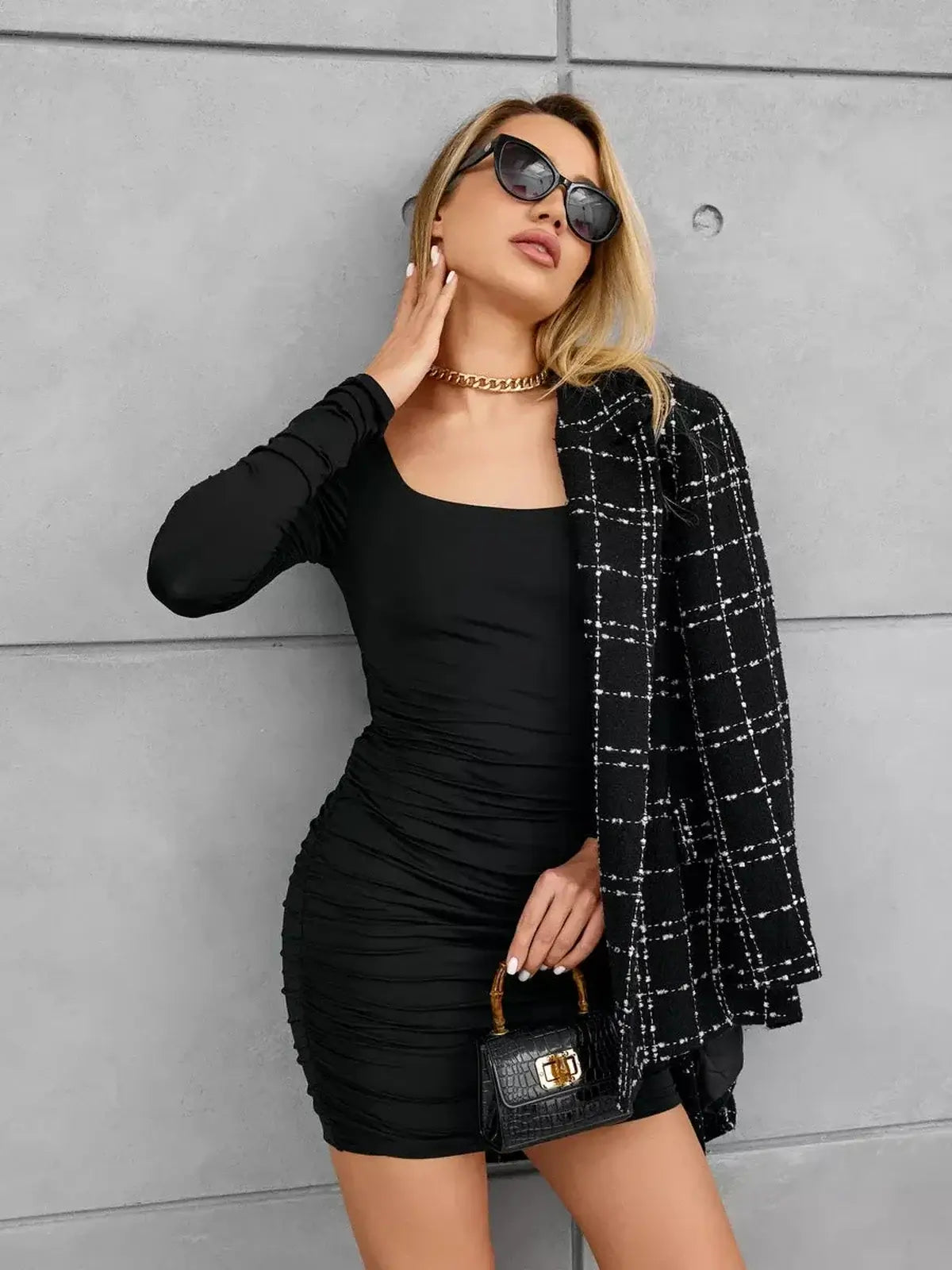 Black mini dress with ruched sides and square neckline, styled with a black blazer and sunglasses.