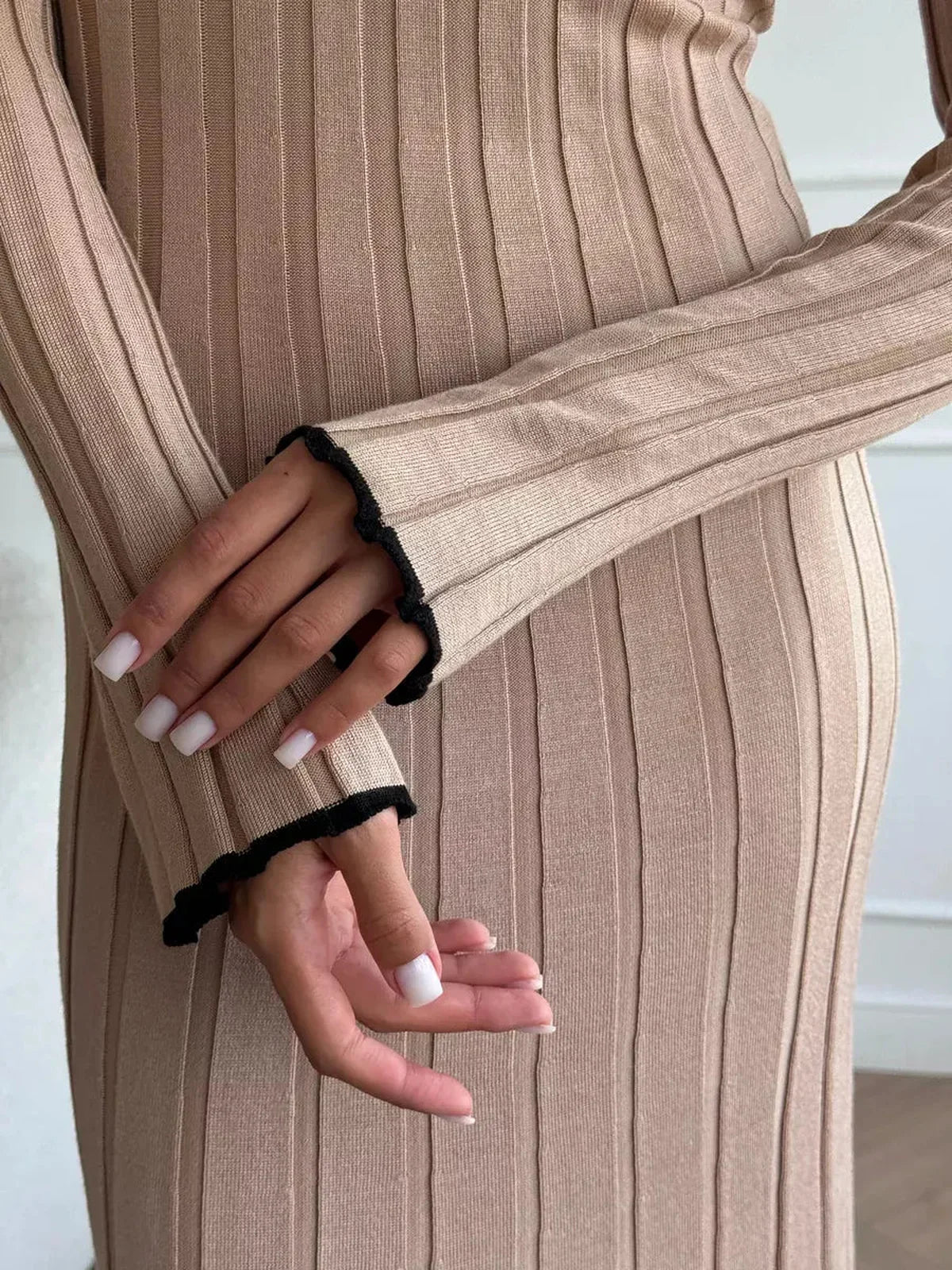 Close-up of hands in Sahara Curve Maxi Dress, showcasing soft ribbed texture and elegant design details in sandstone beige.
