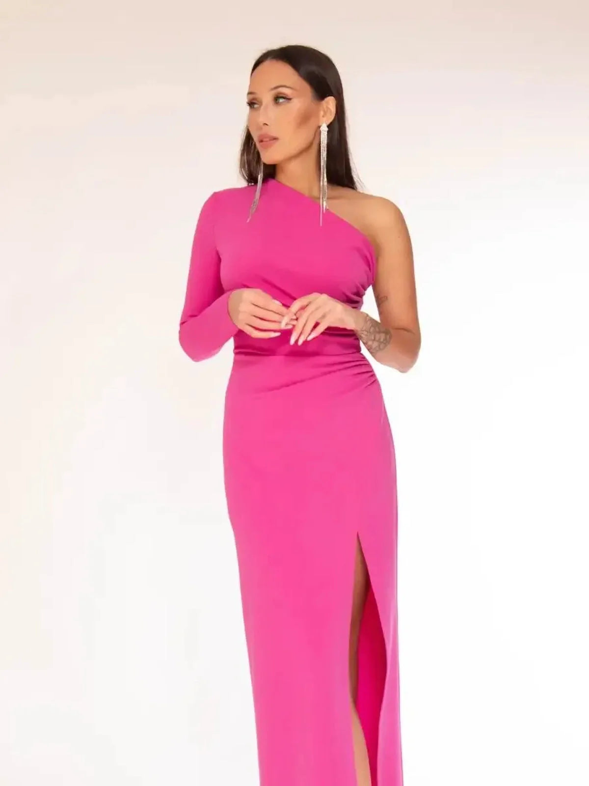 Vibrant pink one-shoulder maxi dress with dramatic thigh-high slit, showcasing elegance and bold style.