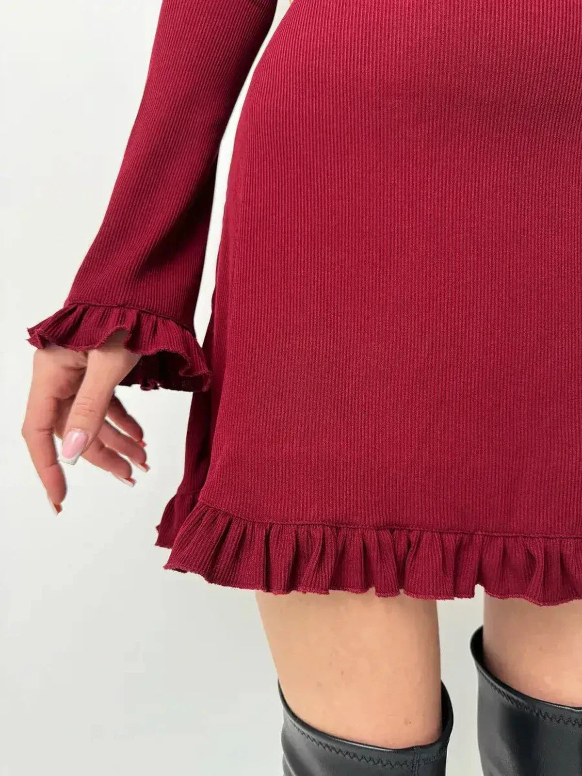 Close-up of a ribbed knit red mini dress featuring romantic ruffles at the cuffs and hem, perfect for a flirty fall look.