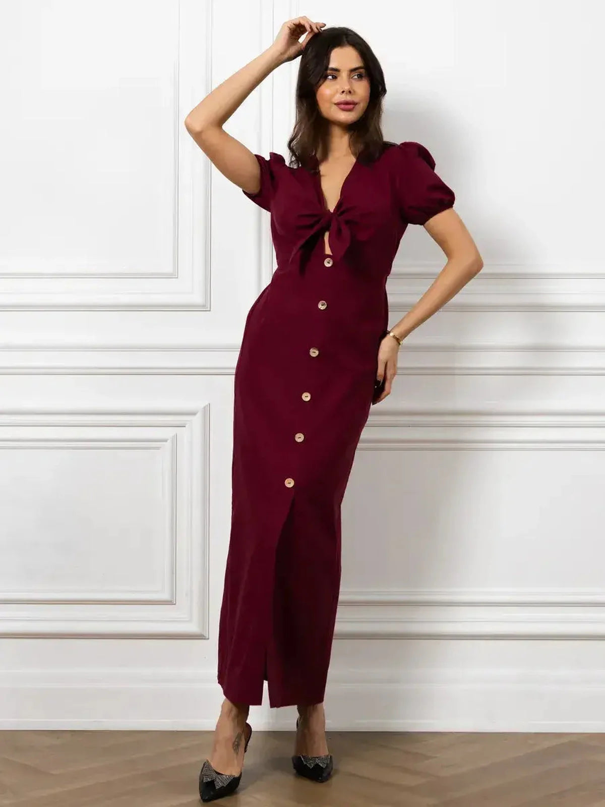 Elegant merlot maxi dress featuring a front bow, button detail, and structured puff sleeves for a sophisticated look.