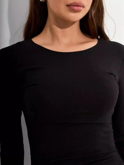 Close-up of a woman wearing a fitted black long sleeve dress with a rounded neckline, showcasing elegance and style.