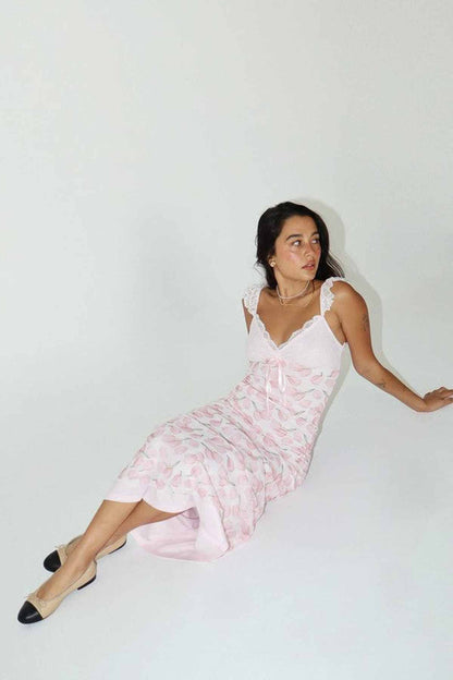 Model wearing a pink floral midi dress with lace detailing, perfect for summer occasions or as a wedding guest outfit.