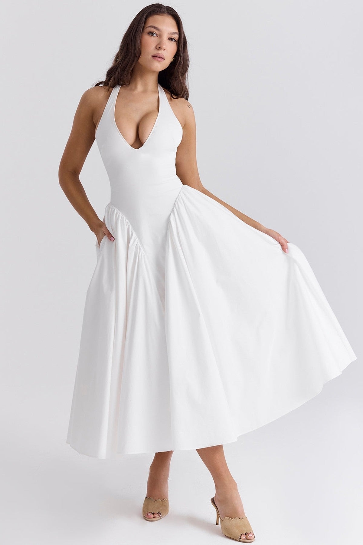 Stylish woman in a white maxi dress with a plunging neckline, showcasing elegant design and flowy skirt.