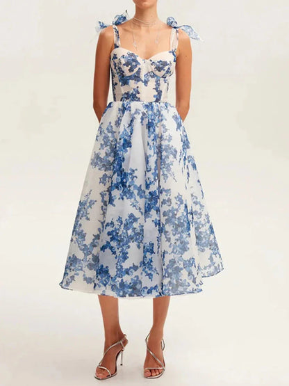 Floral midi dress with blue print and shoulder bows, perfect for weddings and summer occasions.