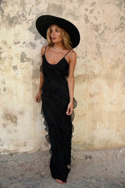 Elegant black maxi dress with ruffled design, worn with a wide-brimmed hat, perfect for summer occasions.