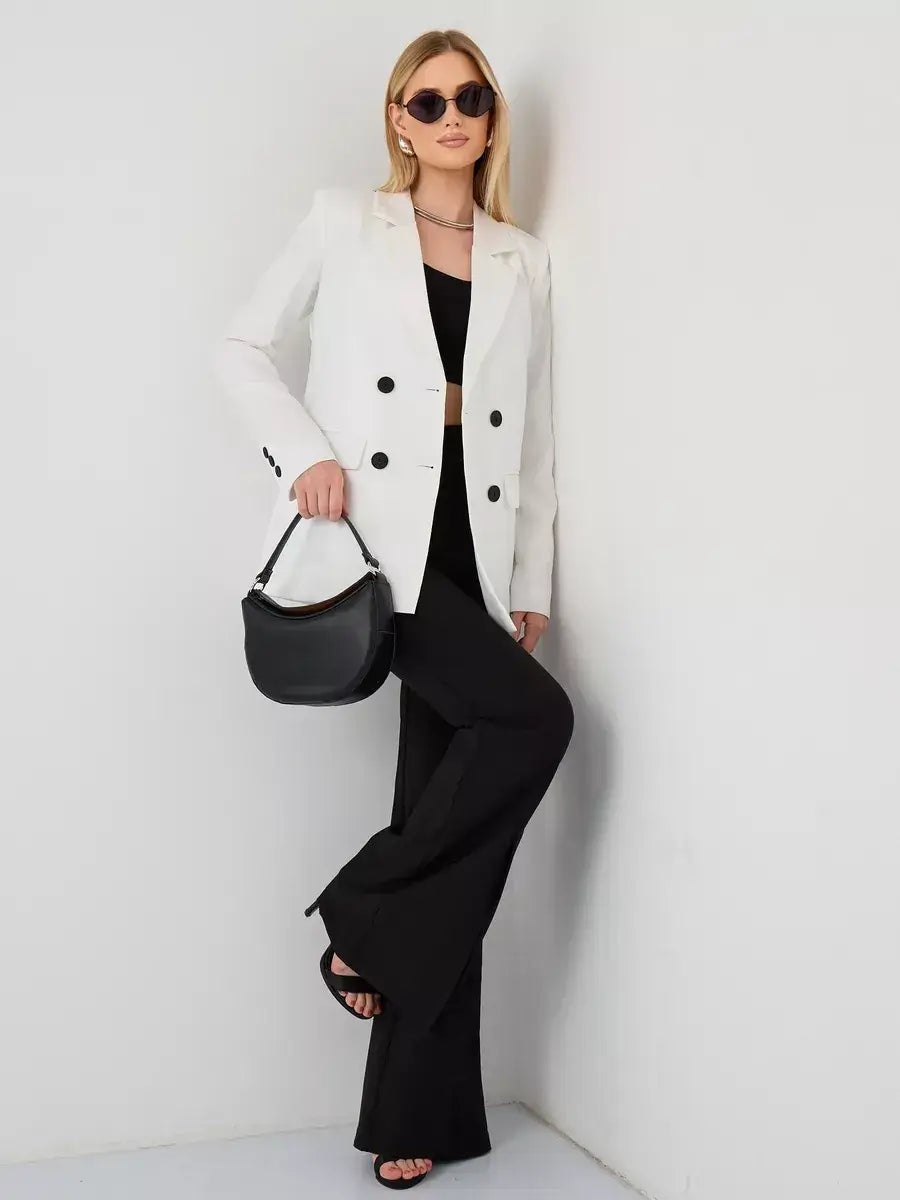 Chic model wearing an Alabaster Blazer with sunglasses, black flared pants, and a stylish bag from Lauven.