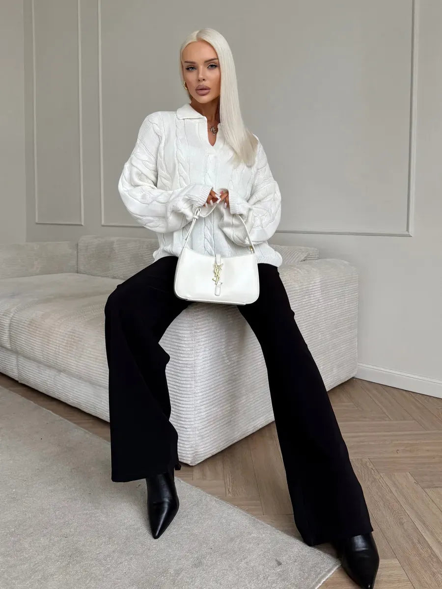 Alabaster Sweater worn by a model, featuring a cable knit design, paired with wide leg pants and a stylish handbag.