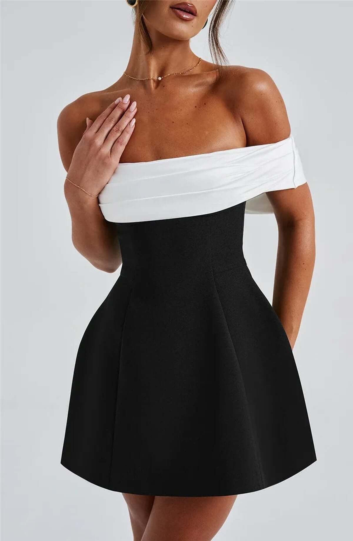 Elegant black and white off-shoulder mini dress featuring an oversized bow, perfect for wedding guests or parties.