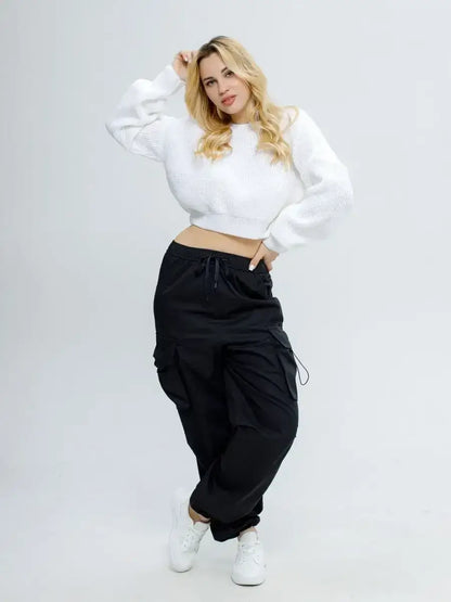 Model wearing Alba Pullover by Lauven, a lightweight white knit with black cargo pants, showcasing trendy comfort.
