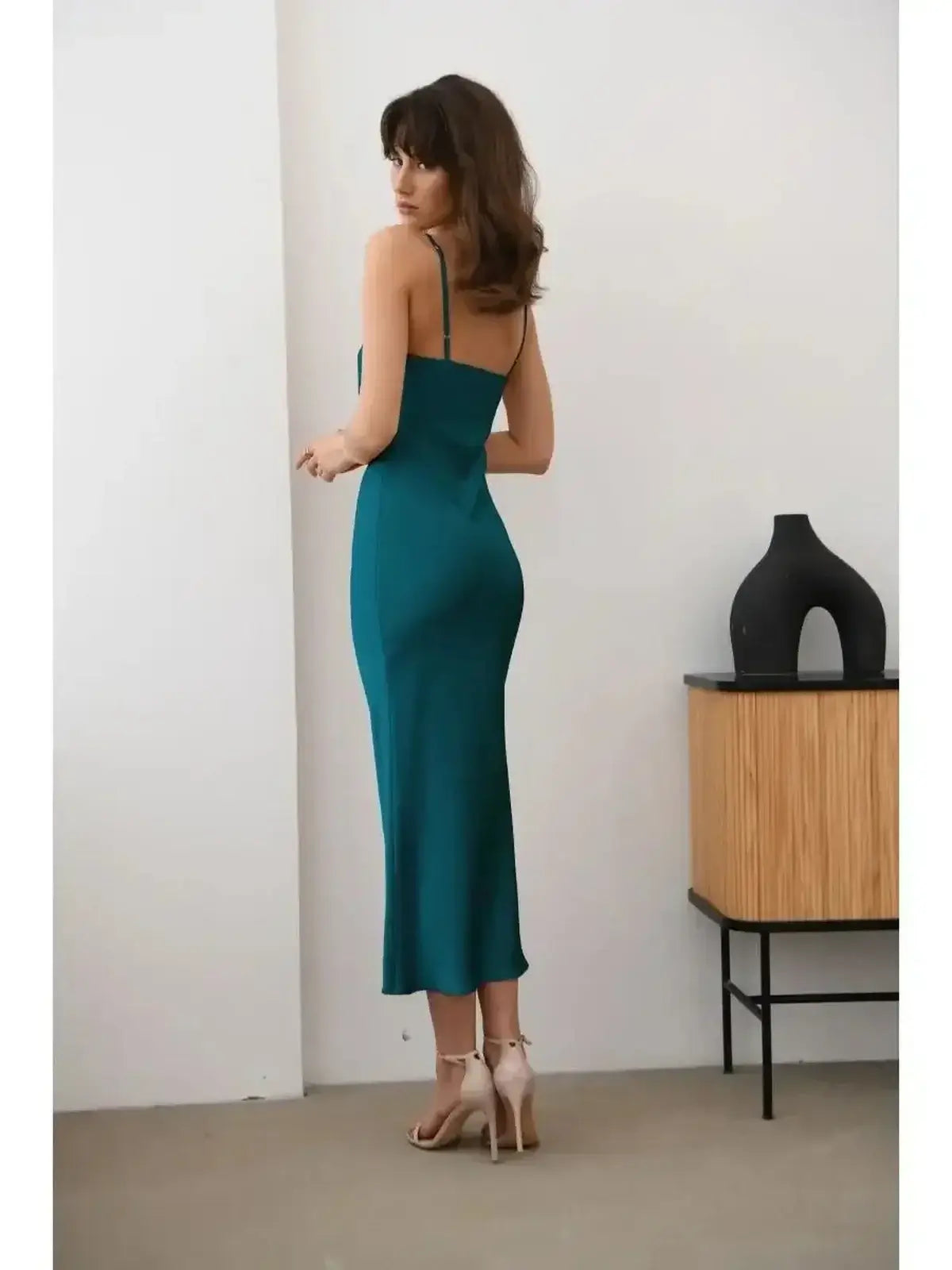 Model showcasing the Allure Midi Dress in emerald green, featuring a sleek silhouette and elegant satin texture.