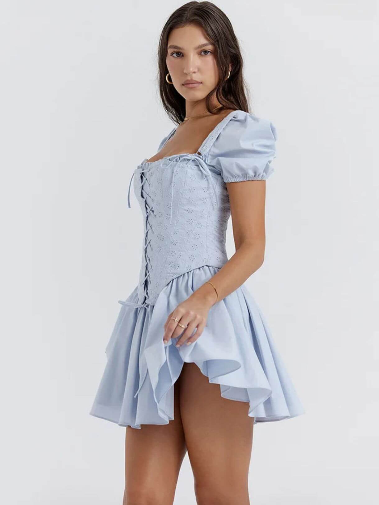 Model wearing the Anya Mini Dress in light blue featuring a detachable corset and playful puff sleeves for summer occasions.