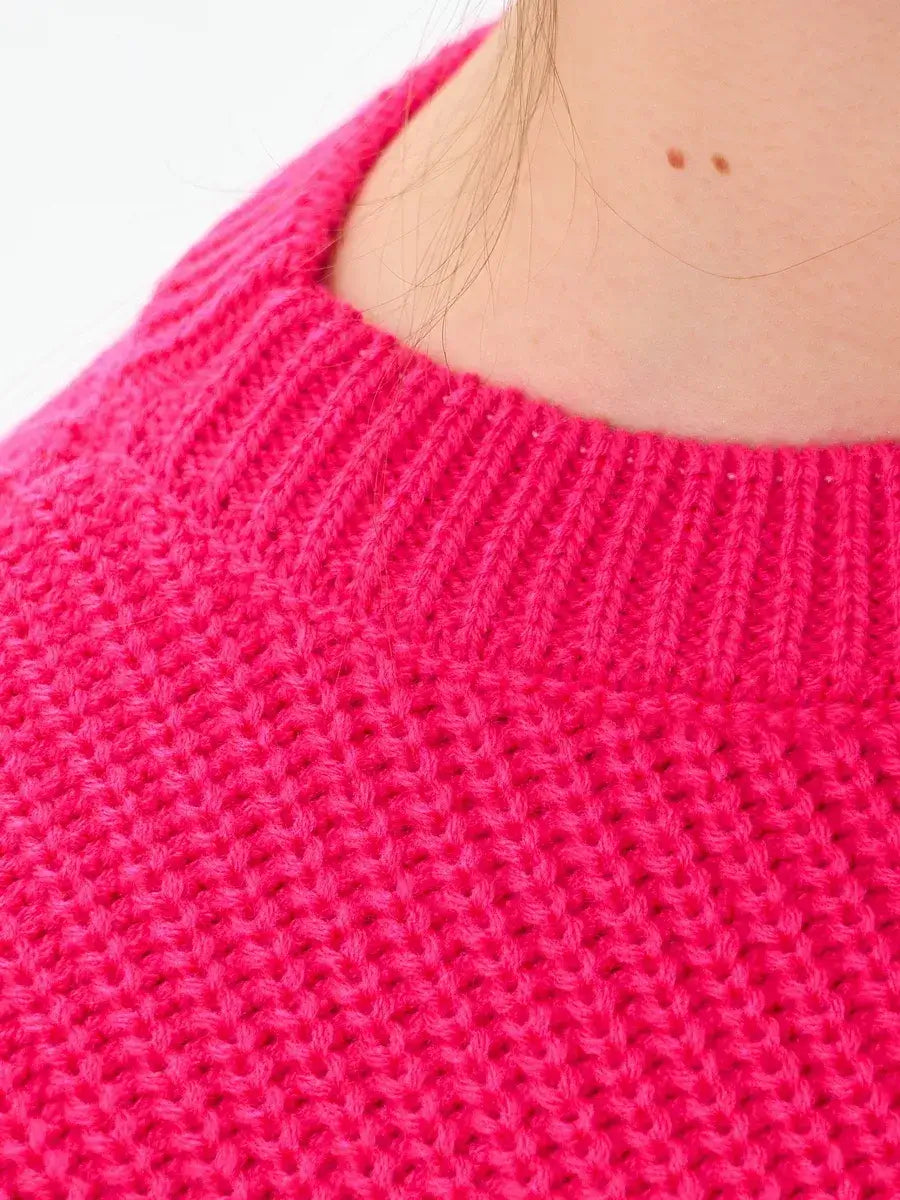 Close-up of an Aster Sweater by Lauven showcasing the vibrant fuchsia knit texture and relaxed neckline.