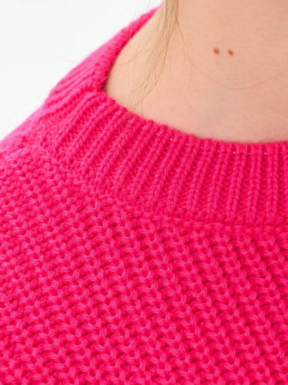 Close-up of an Aster Sweater by Lauven showcasing the vibrant fuchsia knit texture and relaxed neckline.