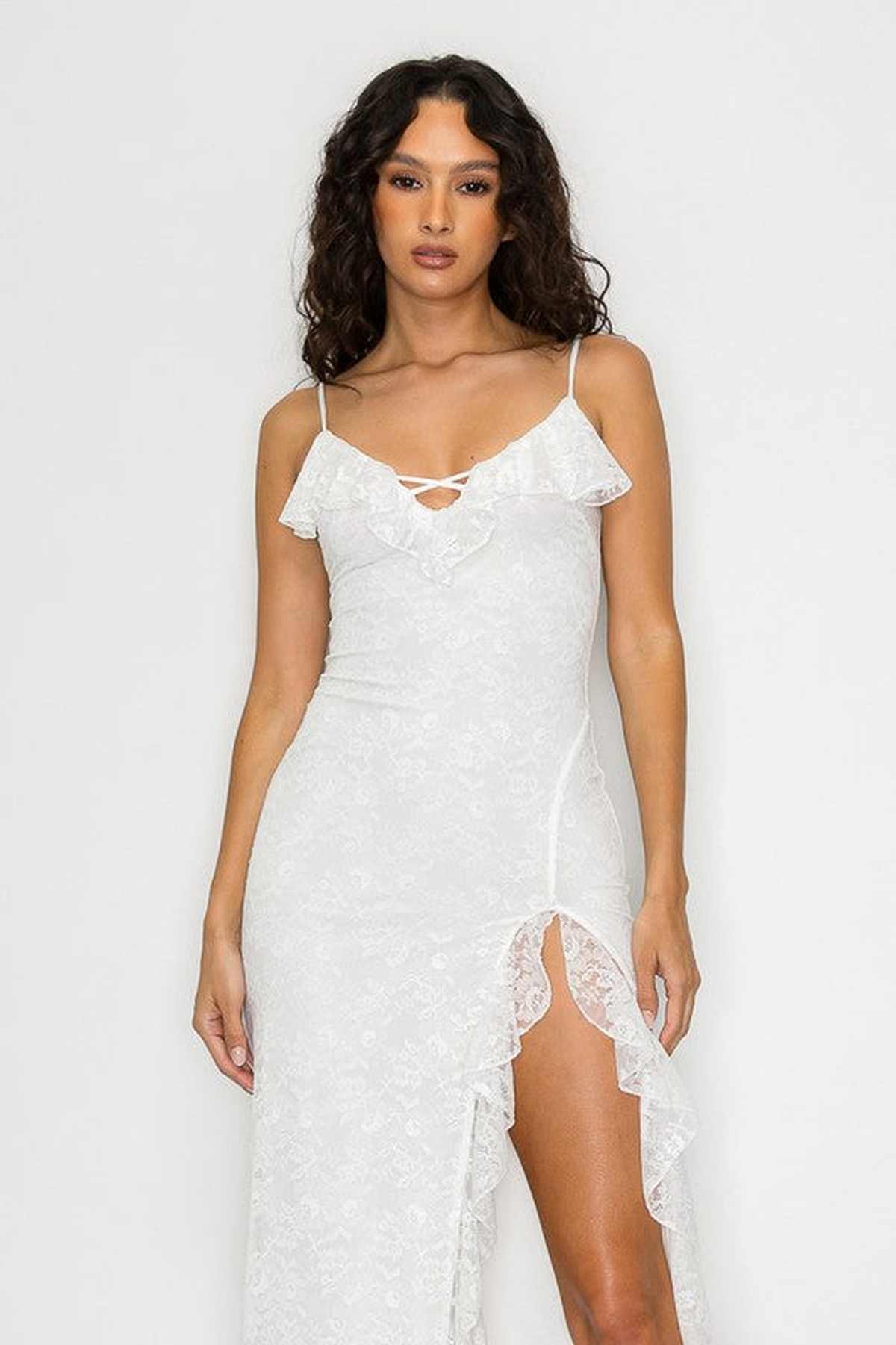 Elegant white maxi dress with floral lace design, ruffled neckline, and thigh-high slit, perfect for weddings and special occasions.