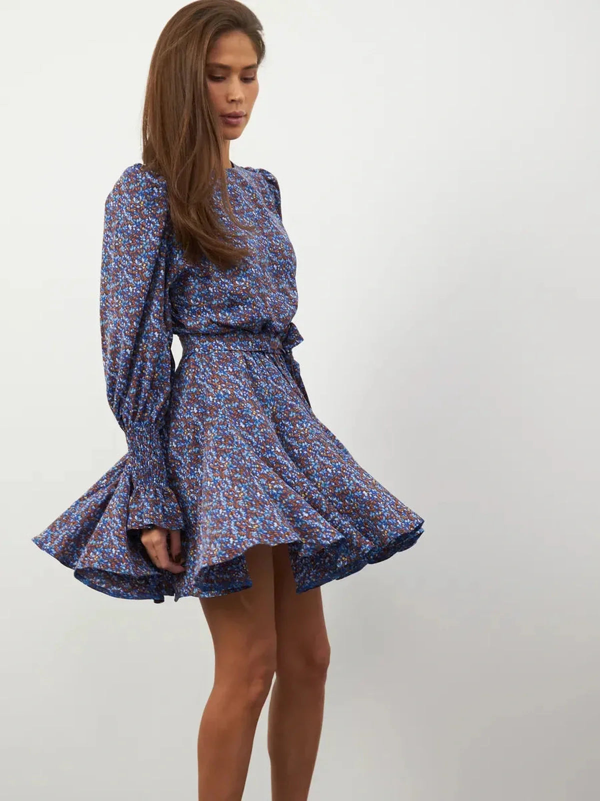 Model wearing the Azure Bloom Mini Dress with vibrant blue floral patterns and flowing silhouette, showcasing elegance and femininity.