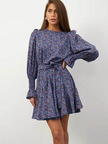 Azure Bloom Mini Dress featuring vibrant blue florals, long sleeves, and delicate ruffles, perfect for effortless elegance.
