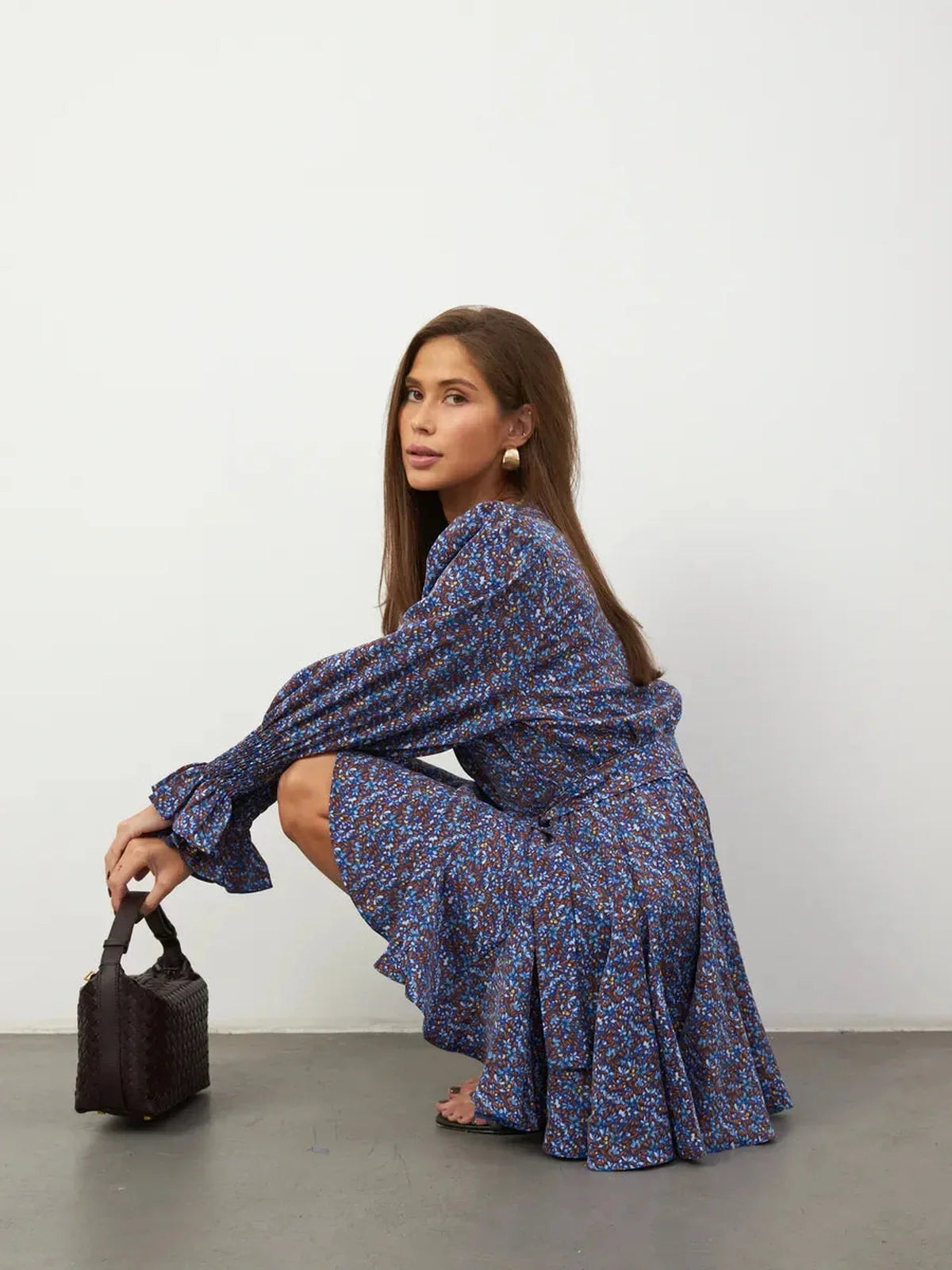 Model showcases Azure Bloom Mini Dress with vibrant blue florals, ruffled hemline, and elegant silhouette.