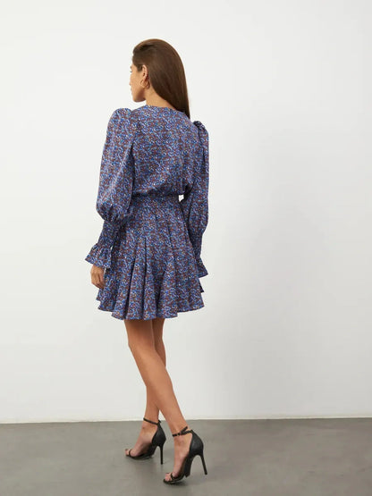 Model wearing the Azure Bloom Mini Dress, showcasing the vibrant blue floral pattern and flowing silhouette from the back.