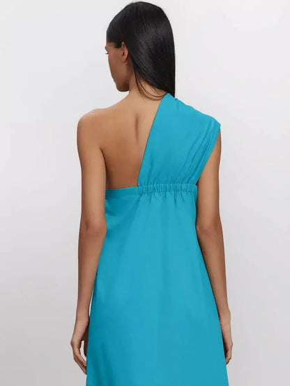 Back view of a woman wearing the Azure Sway Maxi Dress in vibrant turquoise with a one-shoulder design.