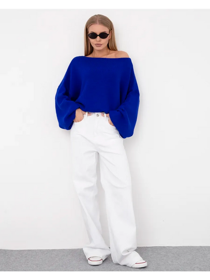 Model wearing an Azure Sweater by Lauven, oversized knit with a boat neck, paired with white jeans and sunglasses.