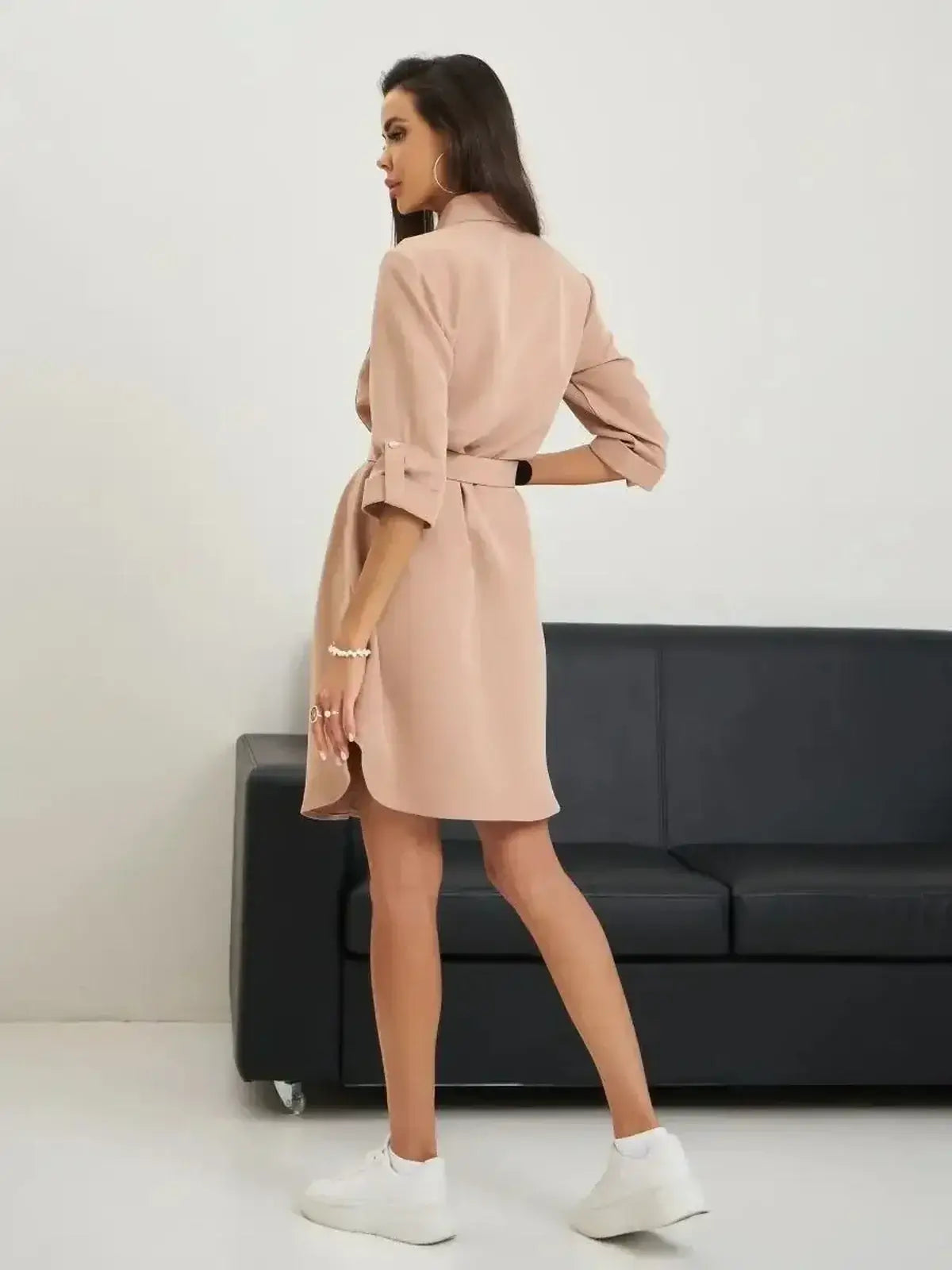 A woman wearing the Belted Chic mini dress in blush, showcasing its structured silhouette and adjustable waist belt.