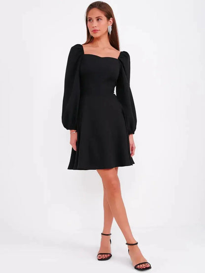 Black mini dress with puff sleeves and square neckline, perfect for cocktail events and wedding guest attire.