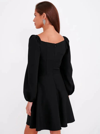 Back view of a black mini dress with puff sleeves and a square neckline, perfect for cocktail or summer occasions.