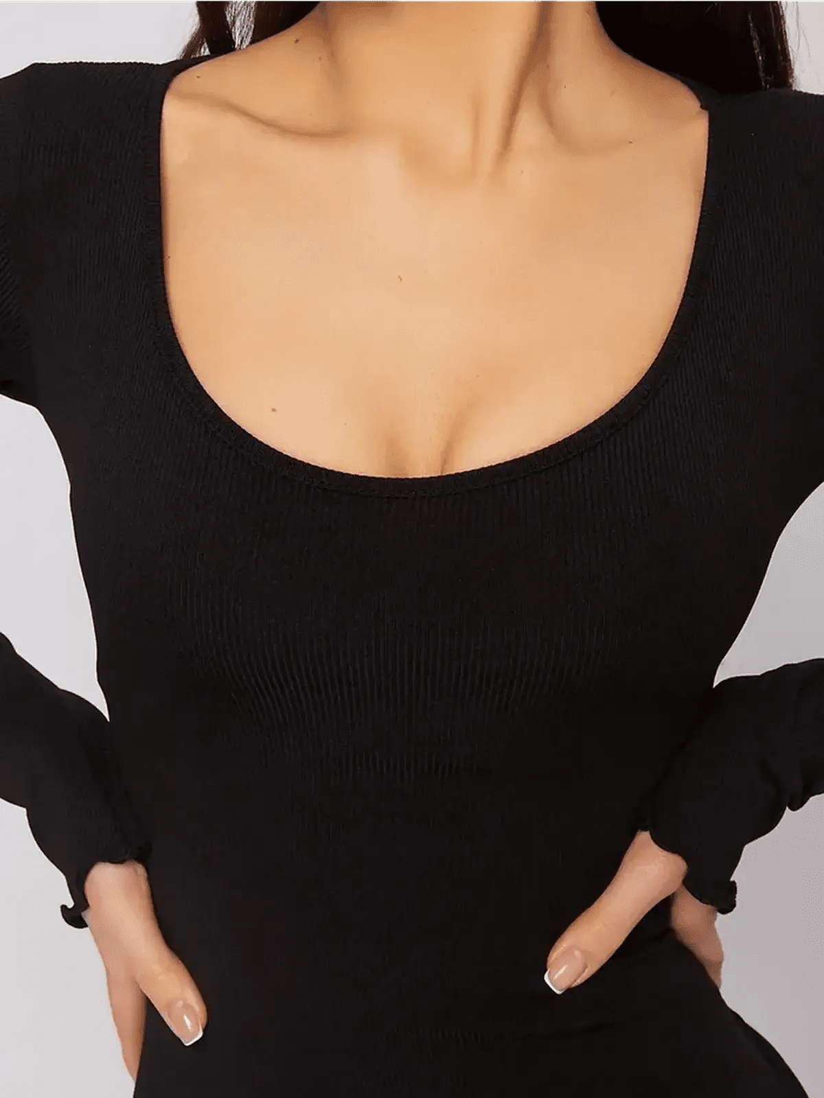 Close-up of a black mini dress with a U-shaped neckline and long sleeves, showcasing a body-hugging silhouette.