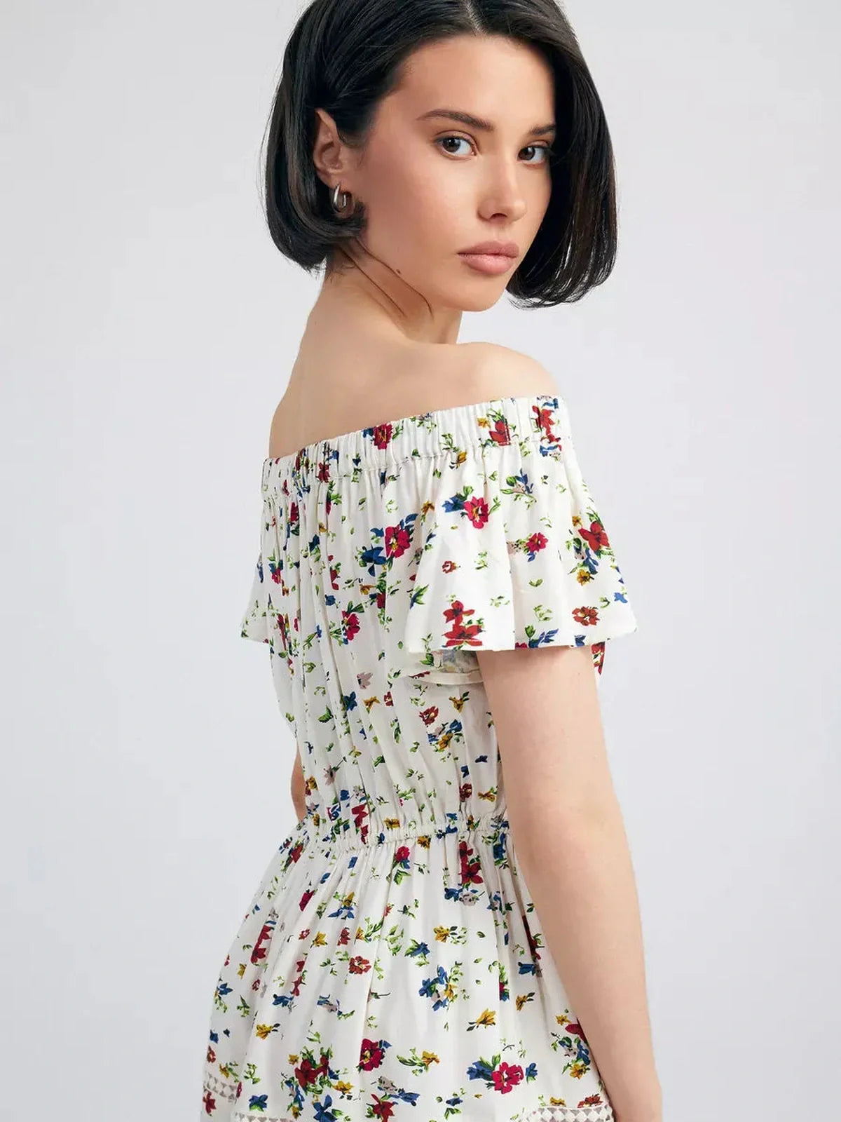 Model showcasing the Bloom Off-Shoulder dress, featuring a delicate floral print and ruffled neckline.