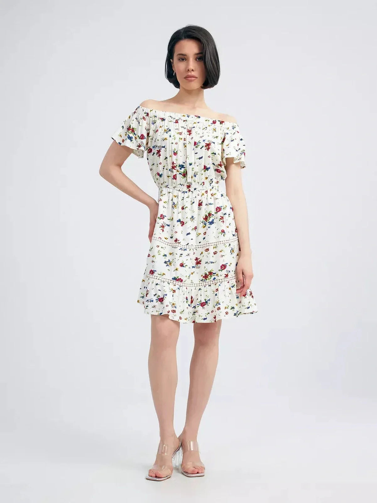 Model wearing the Bloom Off-Shoulder white dress with multicolor floral print and embroidered trims, perfect for summer.