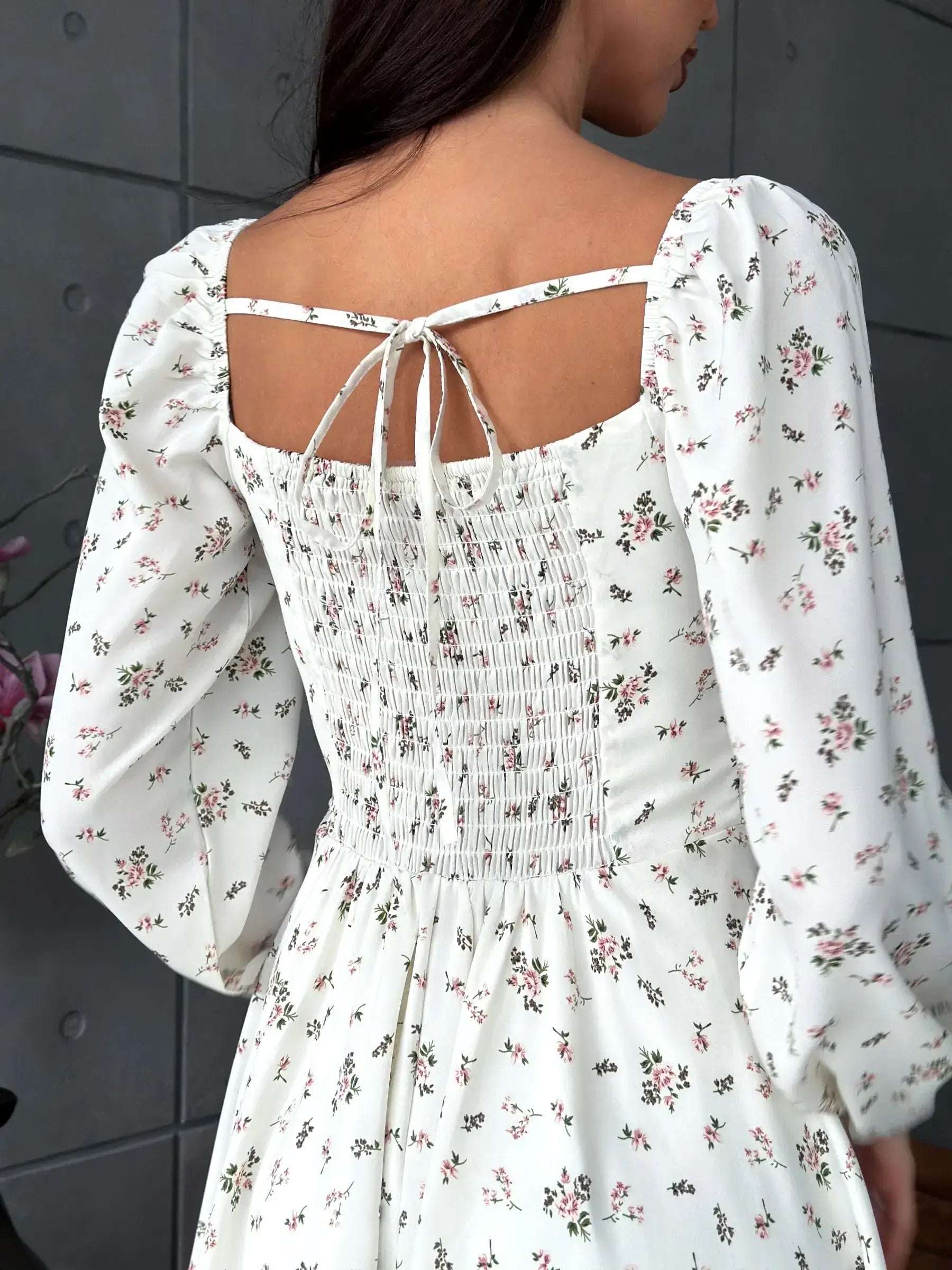 Back view of the Blossom Grace white dress with floral print, featuring a square neckline and smocked bodice design.