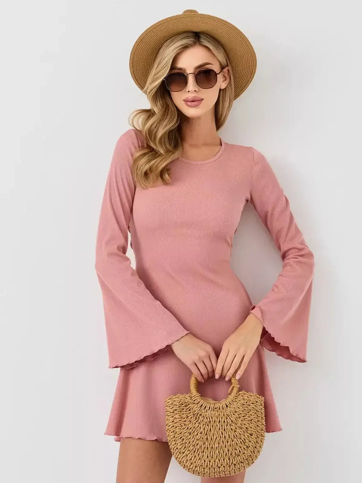 Model wearing the Blush Aura mini dress by Lauven, featuring long flared sleeves and a stylish U-neckline.