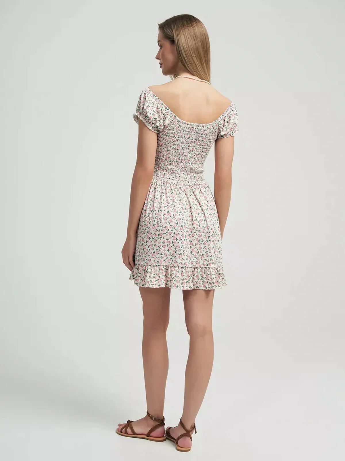Back view of a woman in a floral summer dress with a ruffled hem, perfect for romantic outings.
