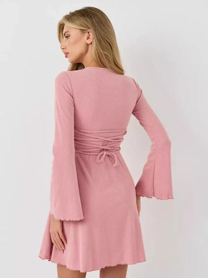 Back view of a model wearing the Lauven Blush Flare mini dress with flared bell sleeves in soft pink.